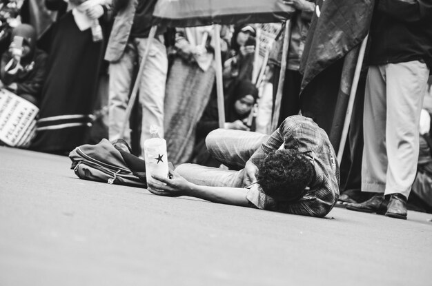 Low section of people sitting on street in city