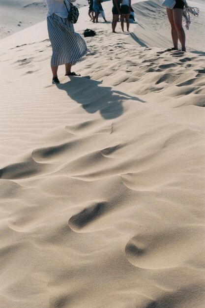 Photo low section of people standing on sand dune