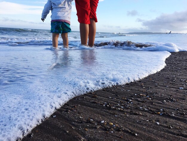 Photo low section of people standing in sea