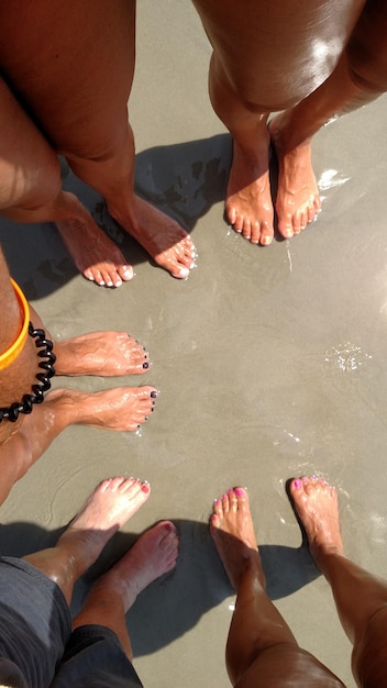 Photo low section of people and their feet standing on beach