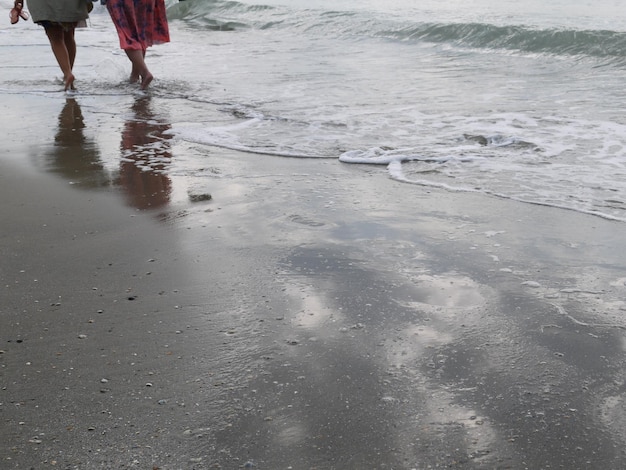 Photo low section of people wading in sea