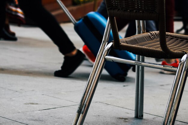 Low section of people walking by chair on footpath