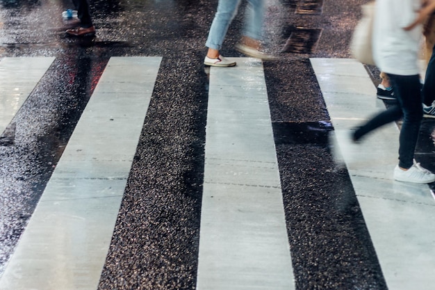 Foto sezione bassa di persone che camminano su una strada bagnata