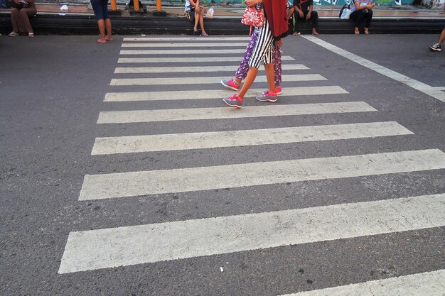 Low section of people walking on zebra crossing