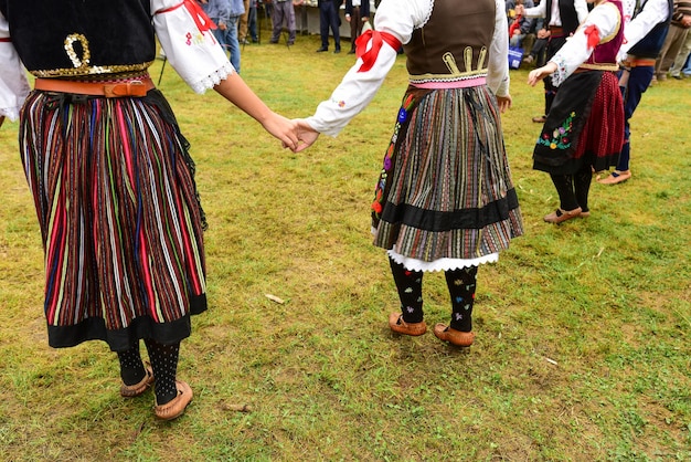 Low section of people wearing traditional clothing while holding hands on grass