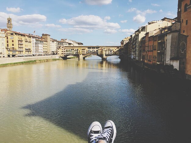 Foto sezione bassa di una persona sul canale tra gli edifici