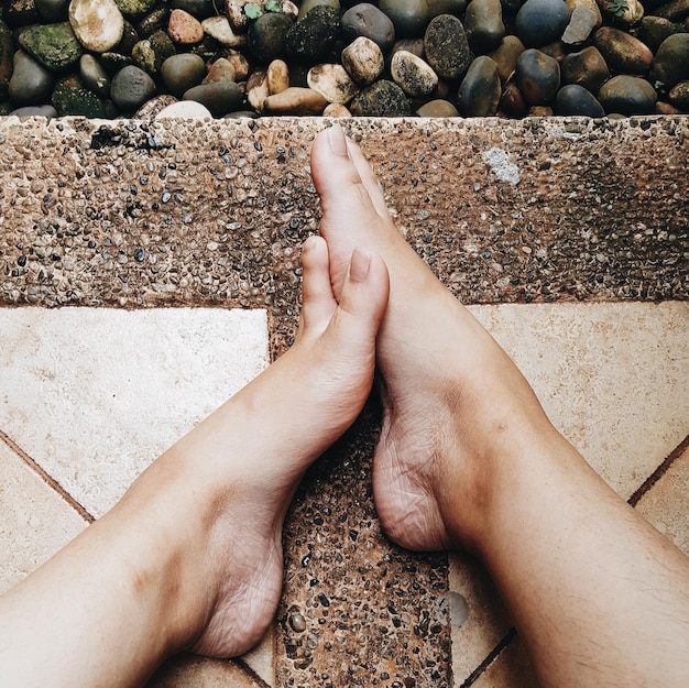 Foto sezione bassa delle gambe di una persona su ciottoli sulla spiaggia