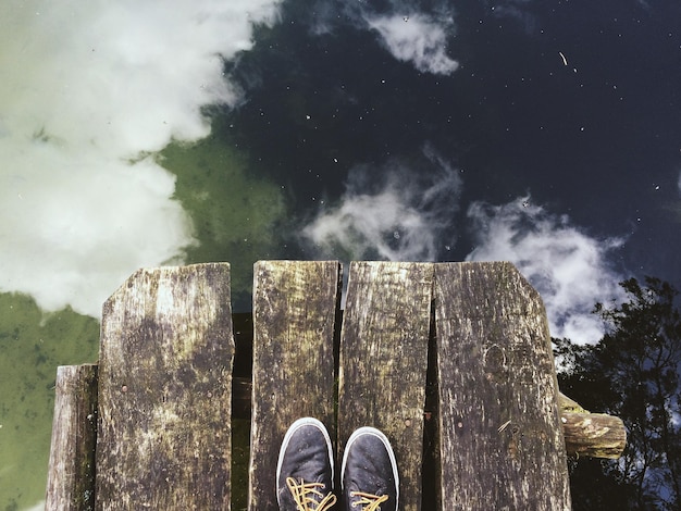 Photo low section of person on pier over lake