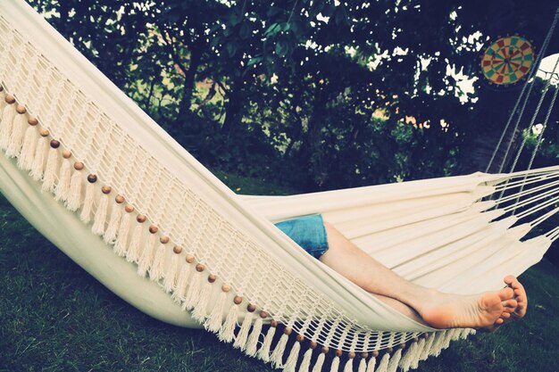 Photo low section of person relaxing in hammock against trees