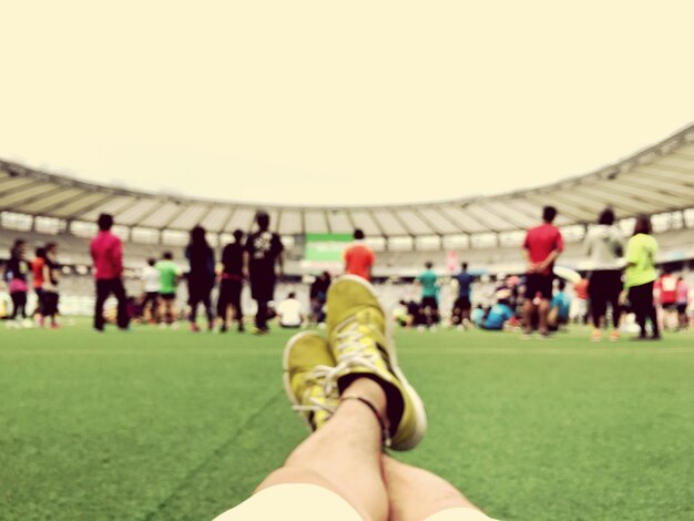 Foto sezione bassa di una persona che si riposa nello stadio da persone contro il cielo