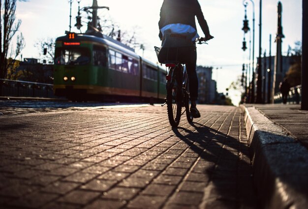 Нижняя часть человека, едущего на велосипеде по пешеходной дорожке в городе