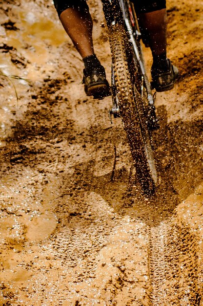 Foto sezione bassa di una persona che va in bicicletta nel fango
