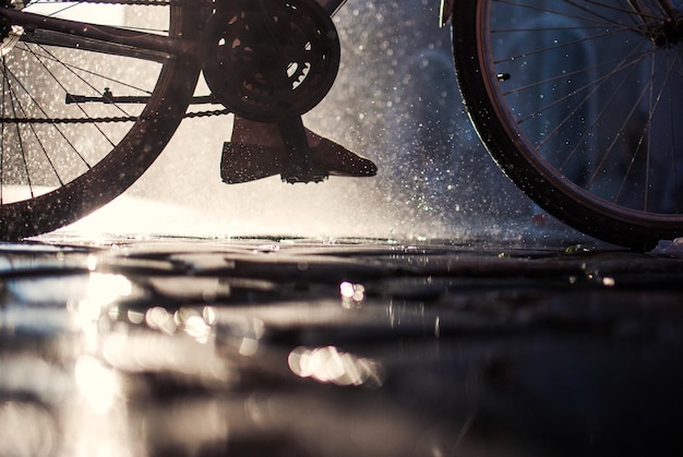 Foto sezione bassa di una persona che va in bicicletta per strada nella stagione delle piogge
