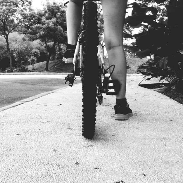 Foto sezione bassa di una persona in bicicletta per strada