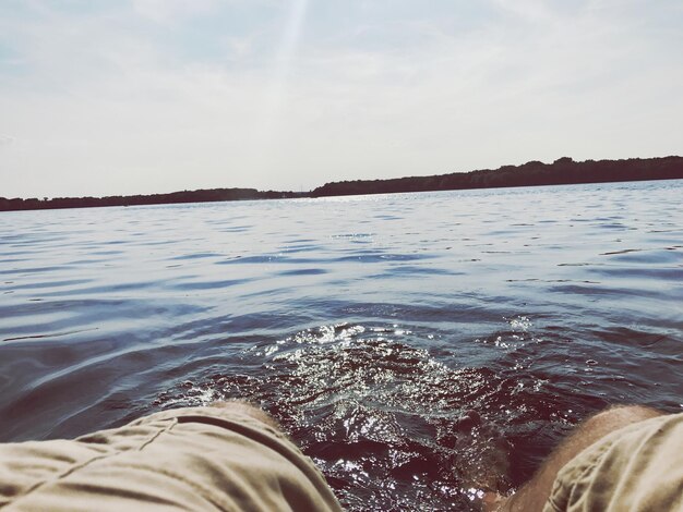 Low section of person in sea against sky