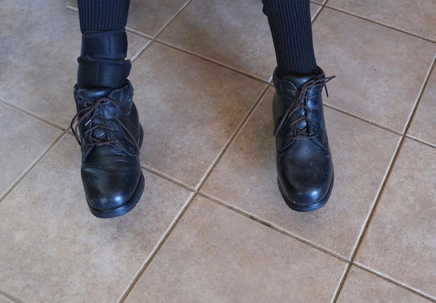 Low section of person in shoe standing on tiled floor