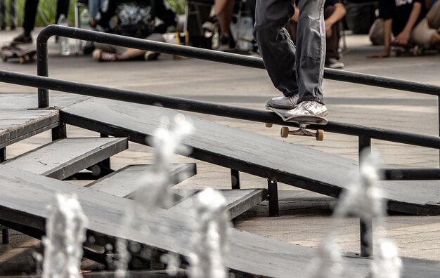 Foto sezione bassa di una persona che fa skateboard su una ringhiera