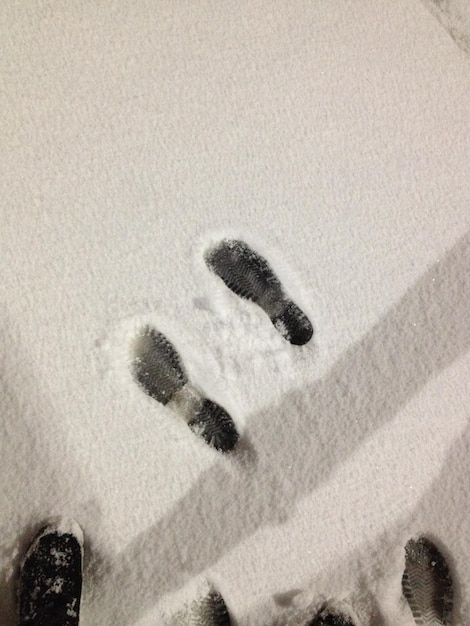 Foto sezione bassa di una persona in piedi per le impronte su un campo coperto di neve