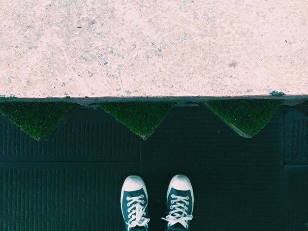 Foto sezione bassa di una persona in piedi sul pavimento di cemento