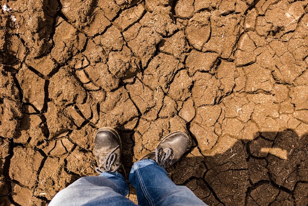 Foto sezione bassa di una persona in piedi su un terreno fessurato