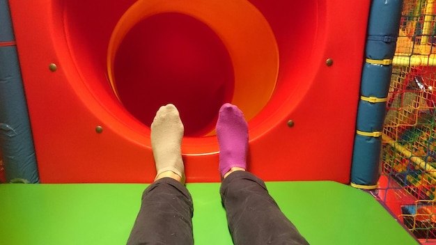 Low section of person standing on hole of tunnel at playground