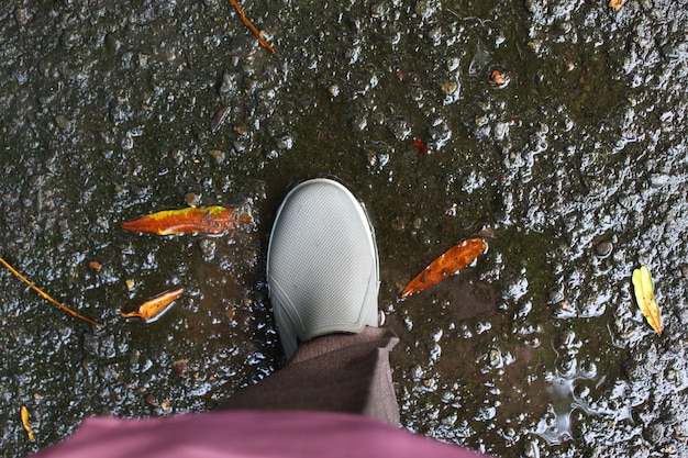 Photo low section of person standing on muddy asphalt