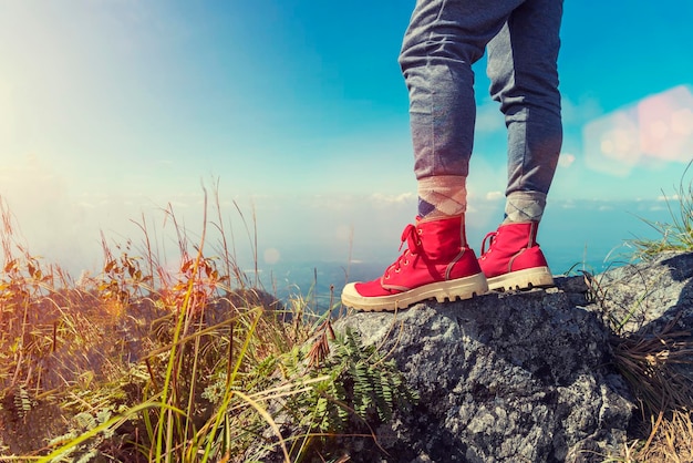 Low section of person standing on rock against sky