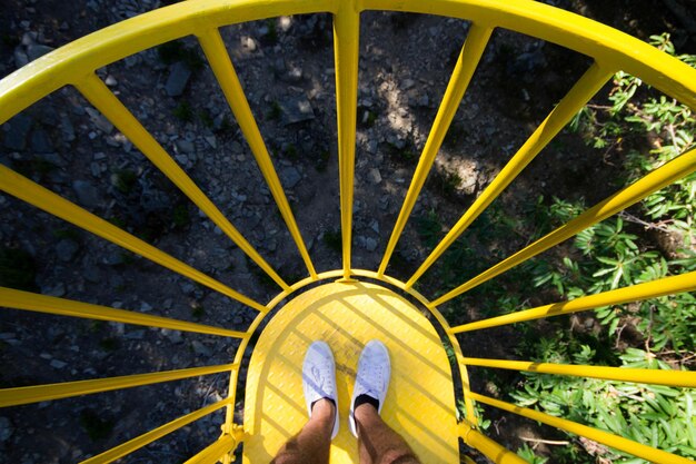 Foto sezione bassa di una persona in piedi su un ombrello giallo