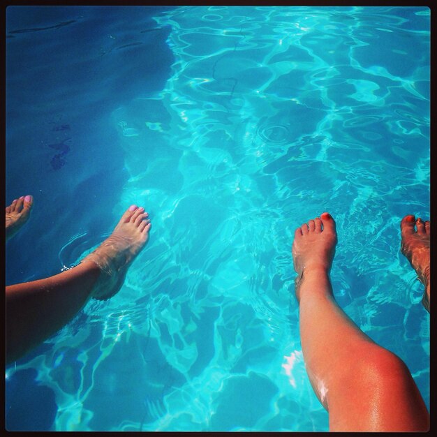 Low section of person swimming in swimming pool