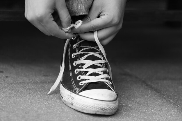 Photo low section of person typing shoelaces on footpath