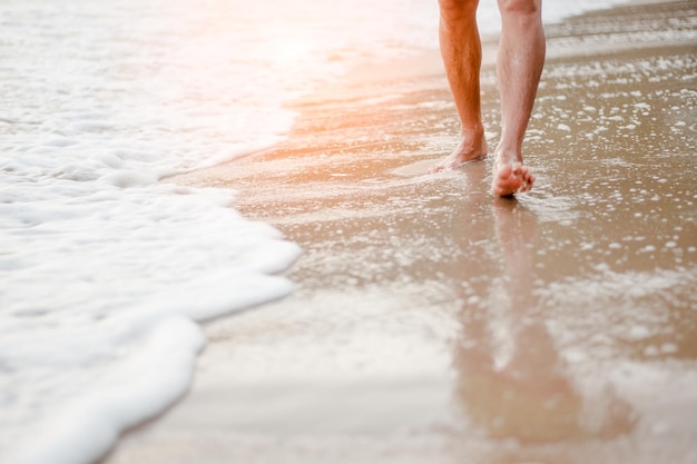 low section of person walking at beach