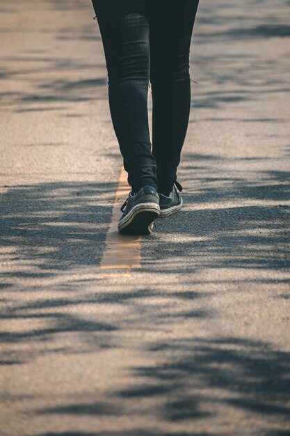 Photo low section of person walking on road in city