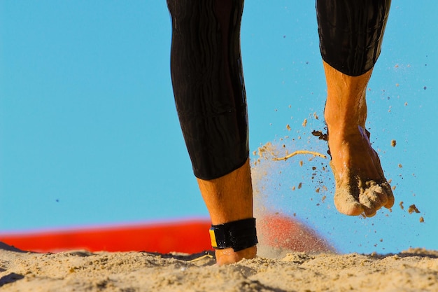 Foto sezione bassa di una persona che cammina sulla spiaggia sabbiosa