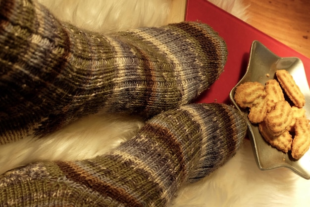 Photo low section of person wearing woolen sock by cookies in star shape plate