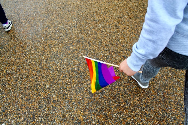 Foto sezione bassa di una persona con una bandiera arcobaleno che cammina sulla spiaggia