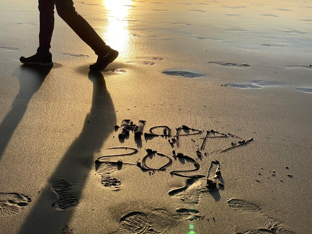 Photo low section of person with text on sand at beach