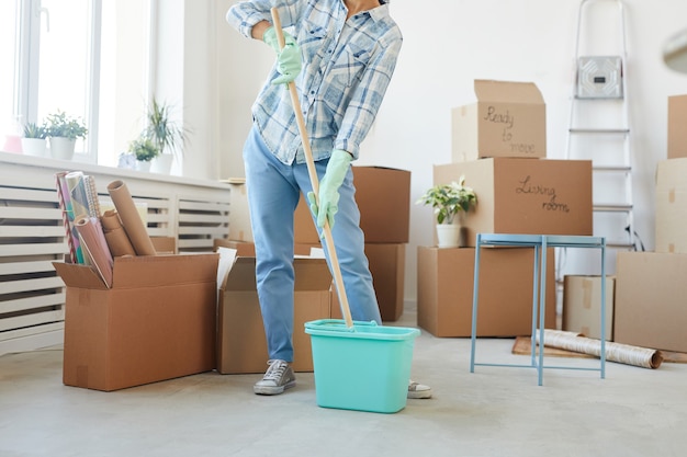 Low section portrait of happy young woman cleaning new house or apartment while moving in