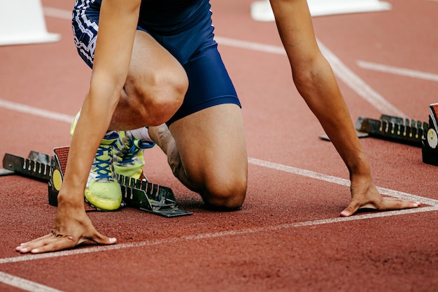 Foto sezione bassa del corridore accovacciato sulla pista di corsa