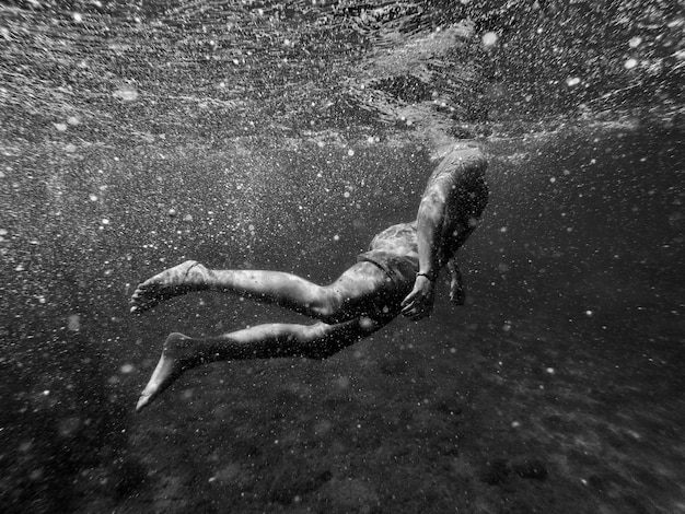 Foto sezione bassa di un uomo senza camicia che nuota in mare