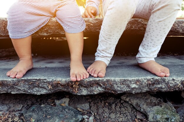 Photo low section of siblings sitting on rock