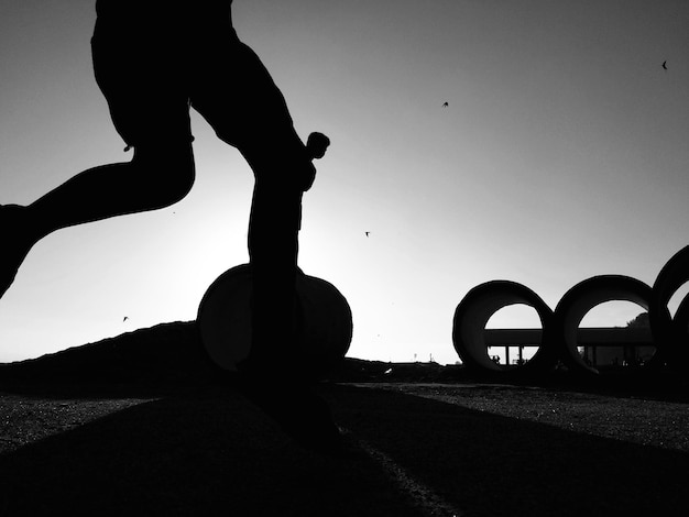 Foto sezione bassa di un uomo a silhouette che corre per strada