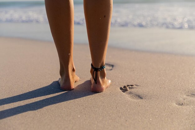 해변에서 시간을 즐기고 바다를 향해 걸어가는 백인 여성의 낮은 단면