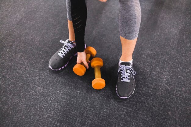 low section view woman picking dumbbell gym