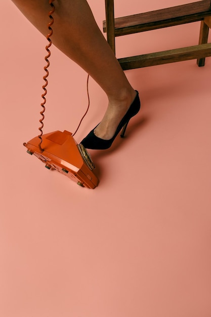 Photo low section of woman by rotary phone on colored background