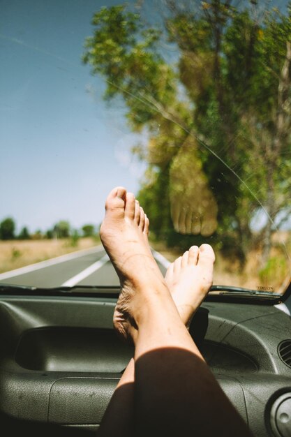 Low section of woman on car against sky