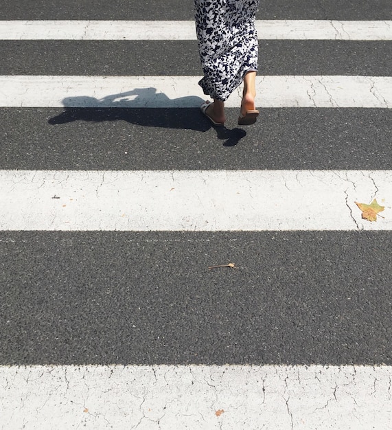 Low section of woman crossing road