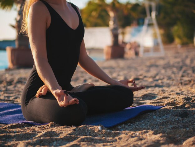 Foto sezione bassa di una donna che fa yoga sulla spiaggia