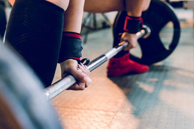 Photo low section of woman holding barbell at gym