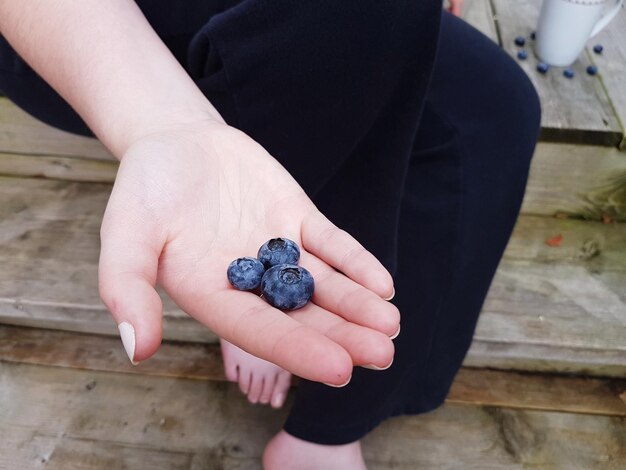 Photo low section of woman holding blueberries in her hand