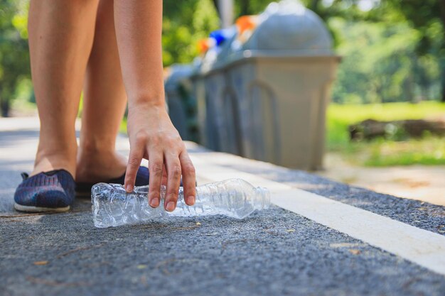 Photo low section of woman holding garage bottle on road